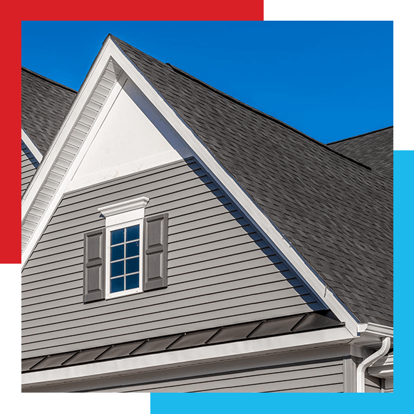 Double gable, with white decorative trim over the windows on a triangle gable roof, gray horizontal vinyl lap siding gable roof private residential new modern house with a window blue sky background